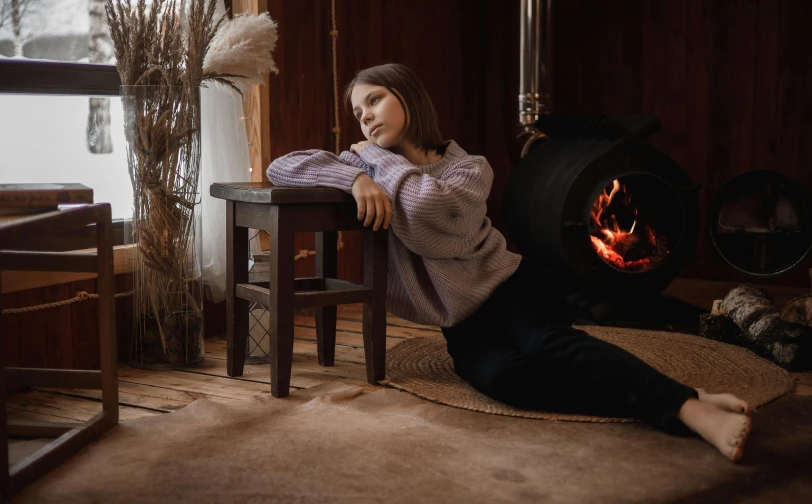 a woman sitting on a chair with her legs up while next to an open fire in a fireplace