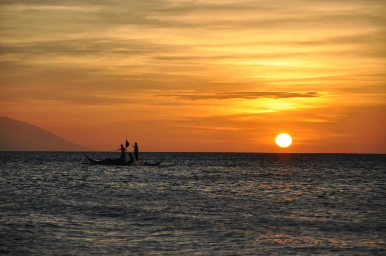 a couple of boats are traveling in the ocean with the sun setting