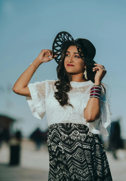 young lady in white shirt and patterned skirt with hat on