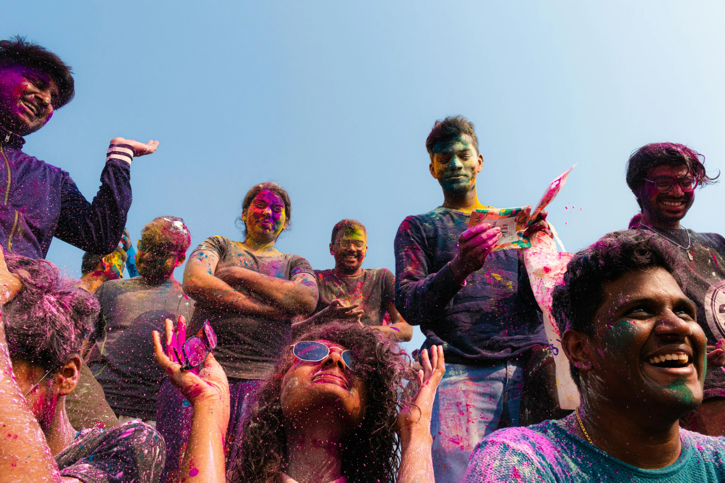 several people with color smeared on their faces stand in front of a crowd