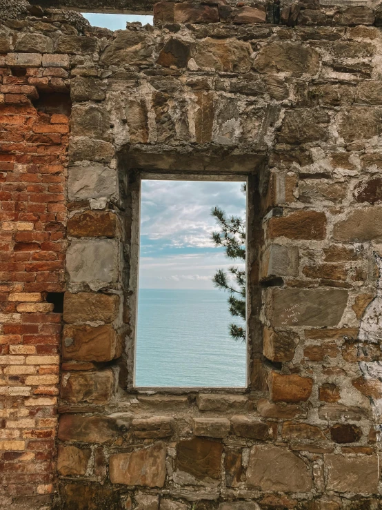 a window view of water through it with stone walls