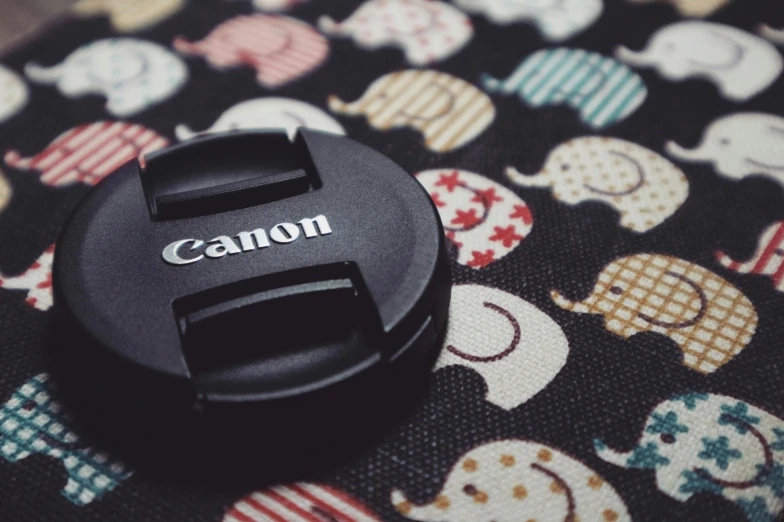 a canon lens cap sits on top of a patterned tablecloth
