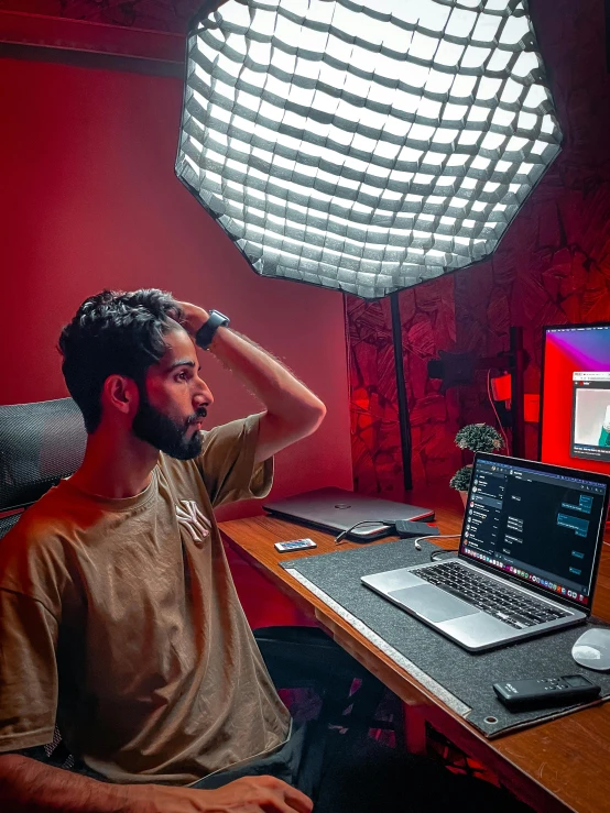 man at computer desk with red lighting, laptop on desk