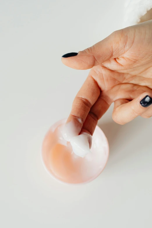 a woman points at a donut with white frosting on it