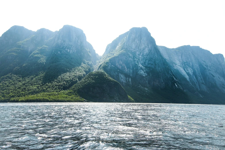 a body of water with green mountains behind it