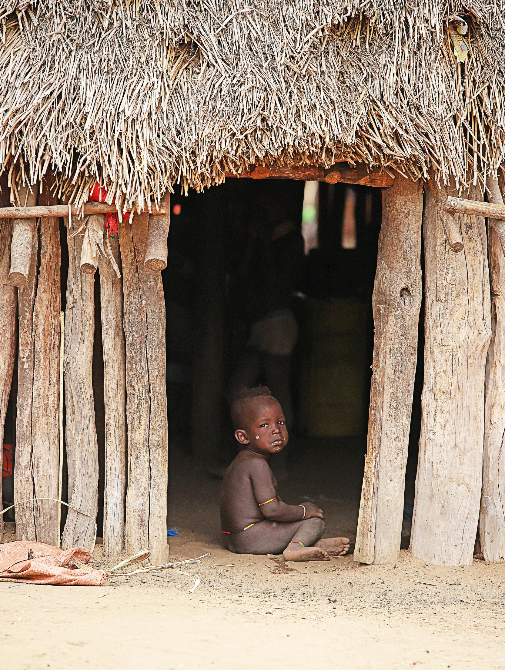 a young person sitting on the floor of a hut