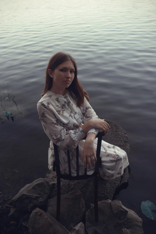 a woman sitting in a chair next to water