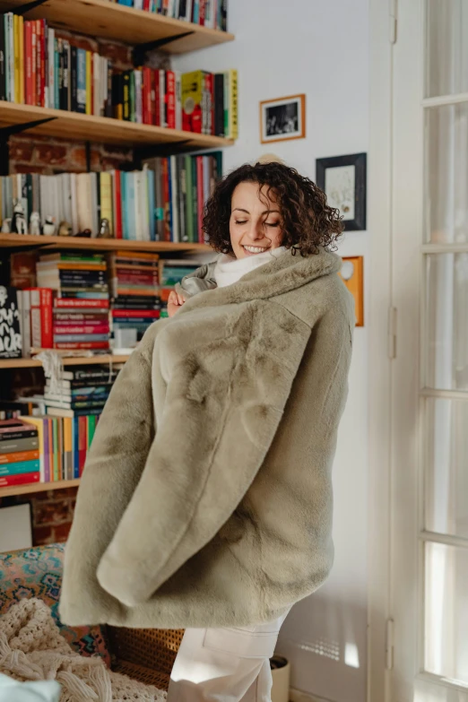 a smiling woman holds onto a large, furry coat