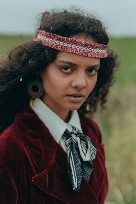 a woman with an afro wearing a red coat and silver necklace