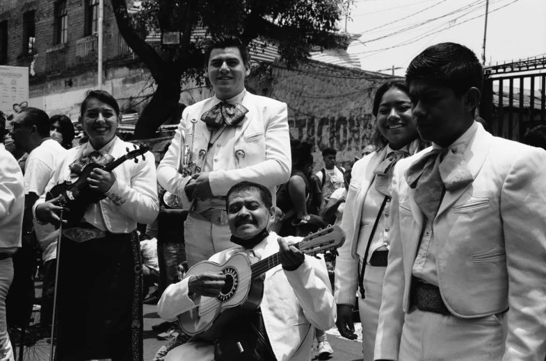 man with white suit and necktie holding a guitar in the street