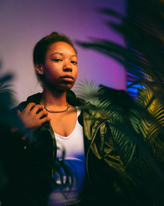 the young woman is posing next to a plant