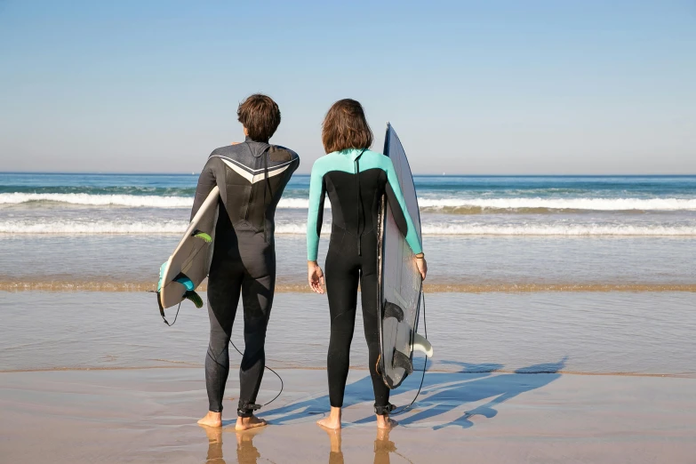 two people are standing in the sand with their surfboards