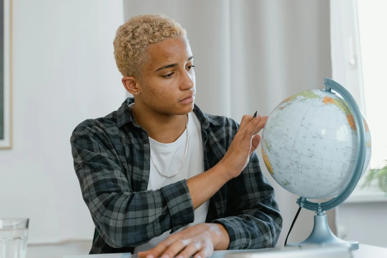 a young man using his cell phone while looking at a globe