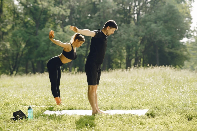 a man and woman doing yoga in the grass