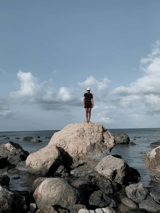 a person standing on top of a rock by the ocean