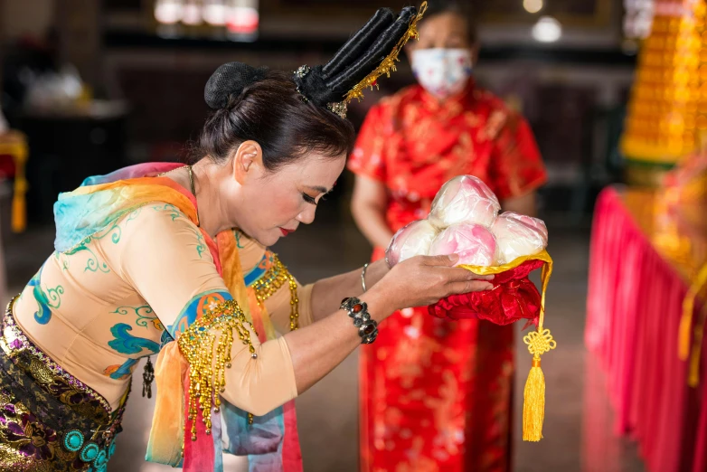 a woman holding a box of flowers and wearing a face mask