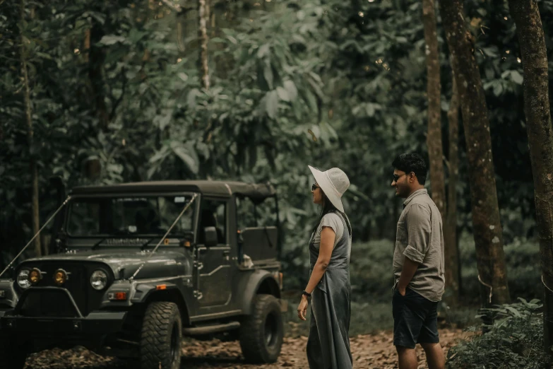 a couple standing in the woods next to an suv