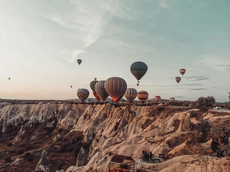 dozens of  air balloons flying over a rocky terrain