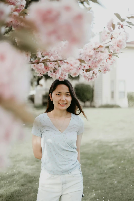 a girl is smiling next to a flowering tree