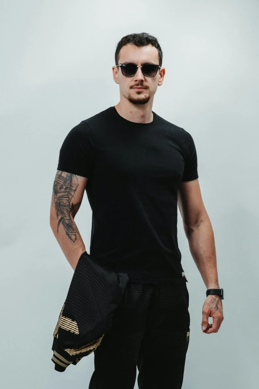 a tattooed man wearing a black shirt and a purse