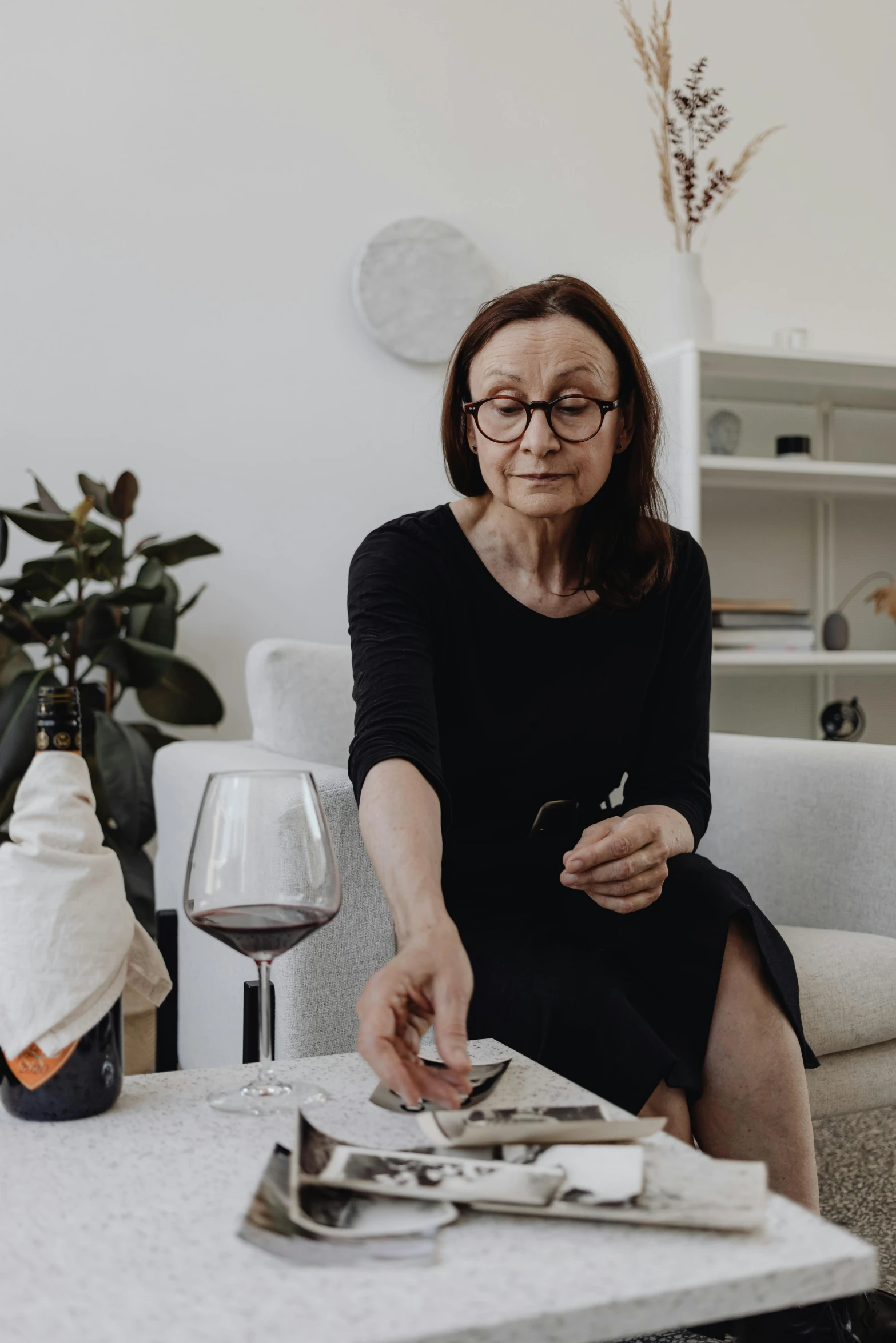 a woman sitting on top of a white couch holding a wine glass