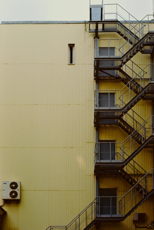 a tan building with metal railings and a stair case