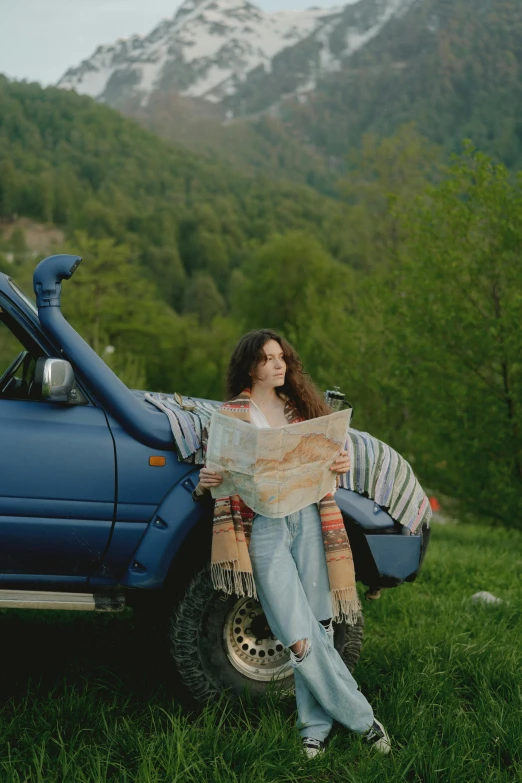 the woman is sitting on a truck looking at the map