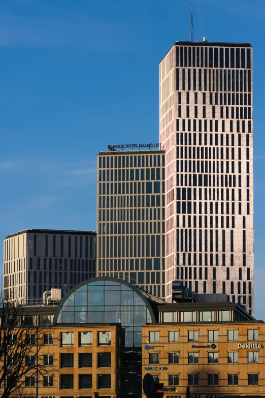 two tall buildings stand next to each other on a sunny day