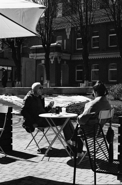 two people sitting at an outside table playing chess