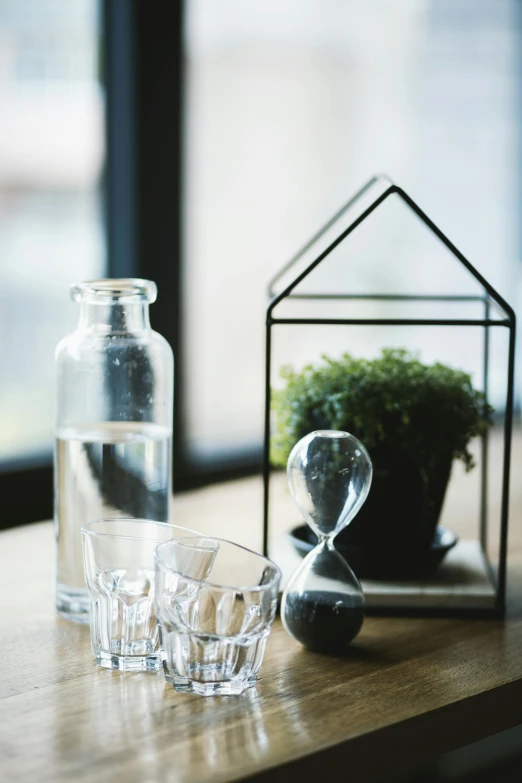 several glasses sitting on a wooden table in front of a small vase