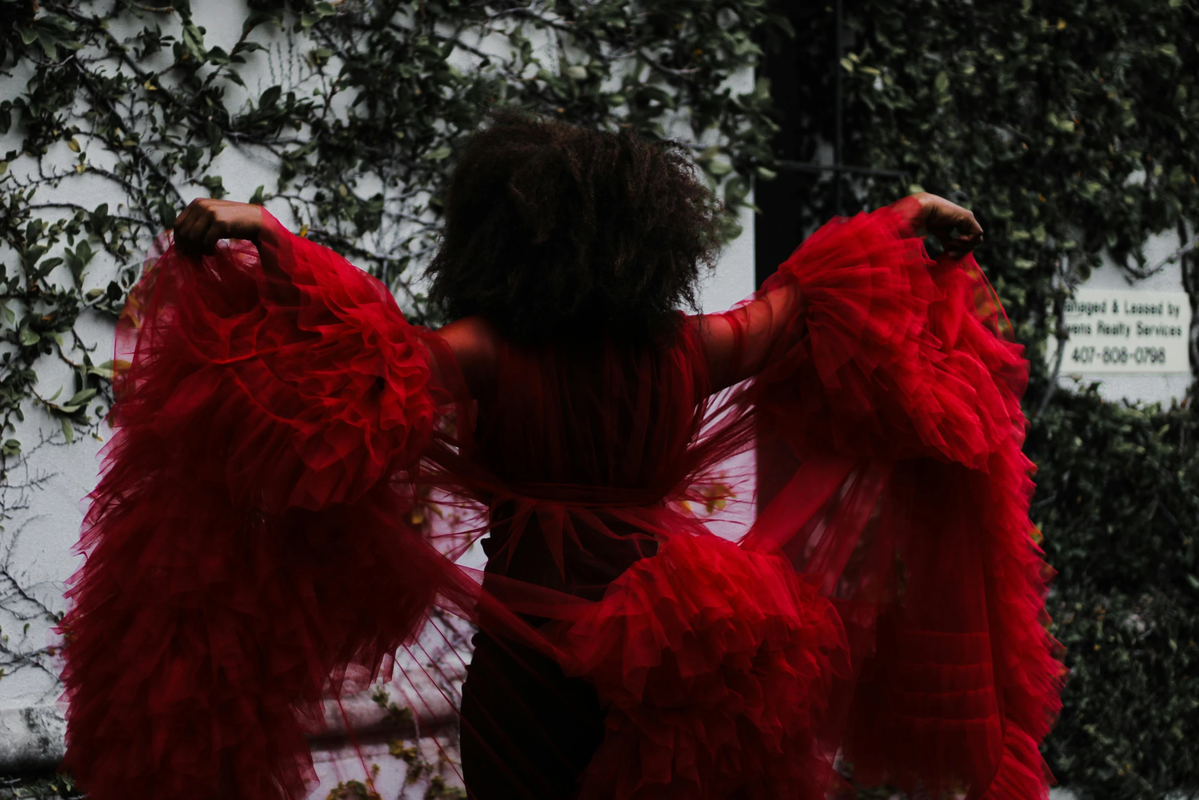 a person dressed in red walking by a building