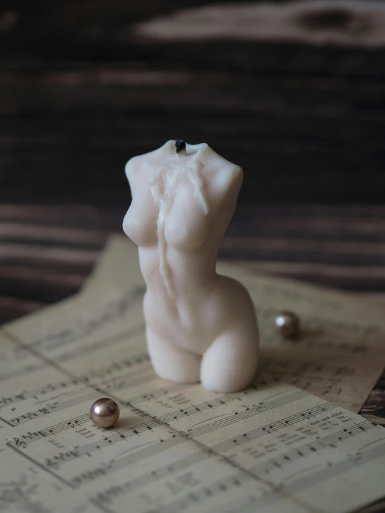a small white sculpture sitting on top of sheet music