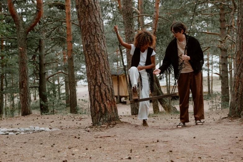 two people standing by some trees, and one holding a bag