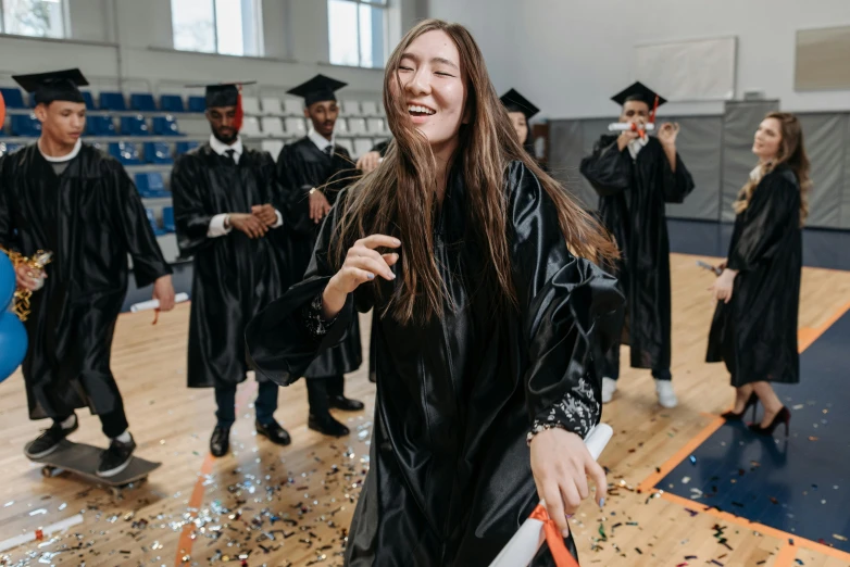 people in gowns stand in a gym to take pictures with their cell phones