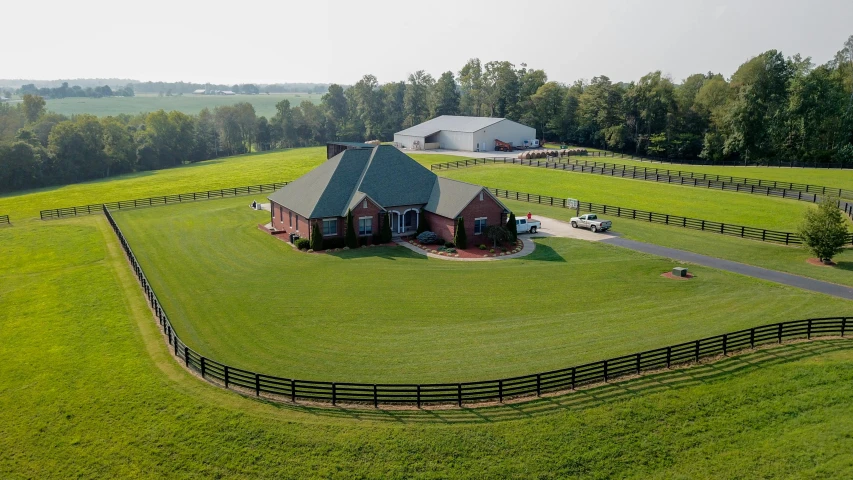 an aerial view of a large horse barn and its surrounding driveway
