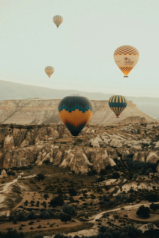  air balloons flying in the sky above a mountainous area