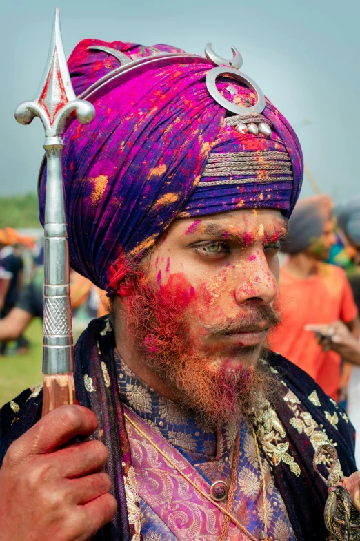 a man in an ornate purple turban holds a stick