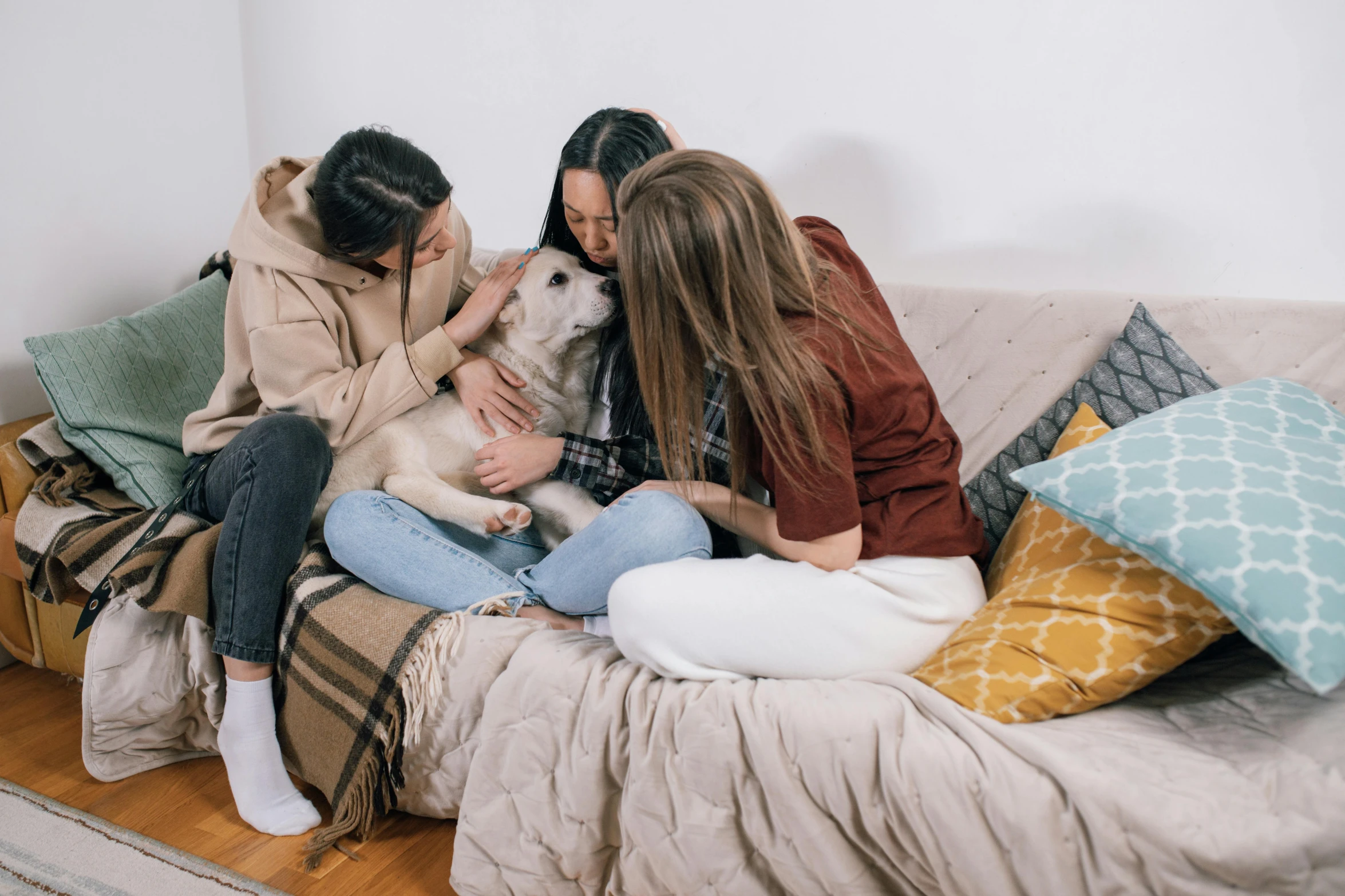 three women and a dog sitting on a couch