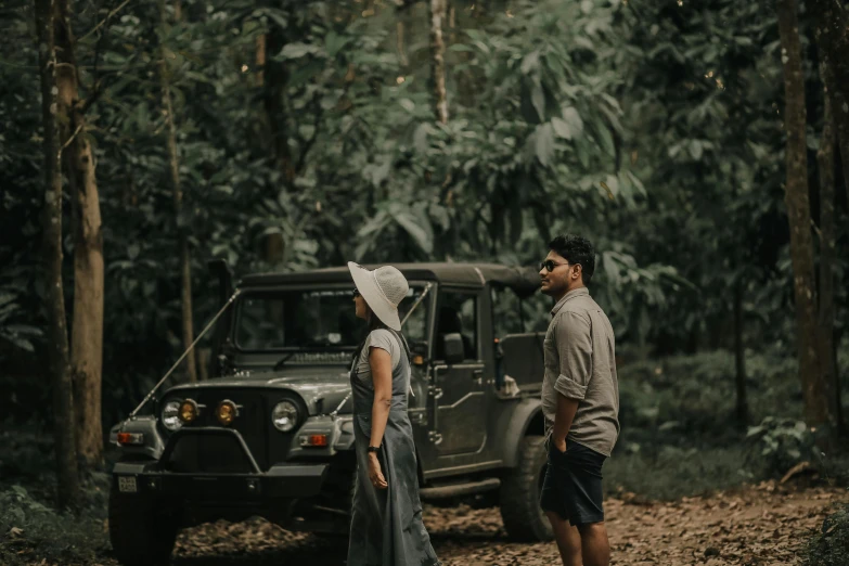 a couple is looking at a black truck on the side of the road