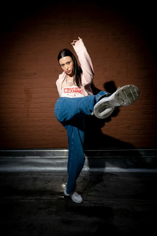 the young woman in a sweatshirt and jeans is dancing outside