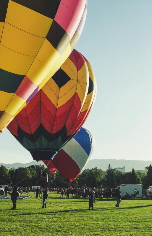 a group of people standing on top of a green field flying large balloons