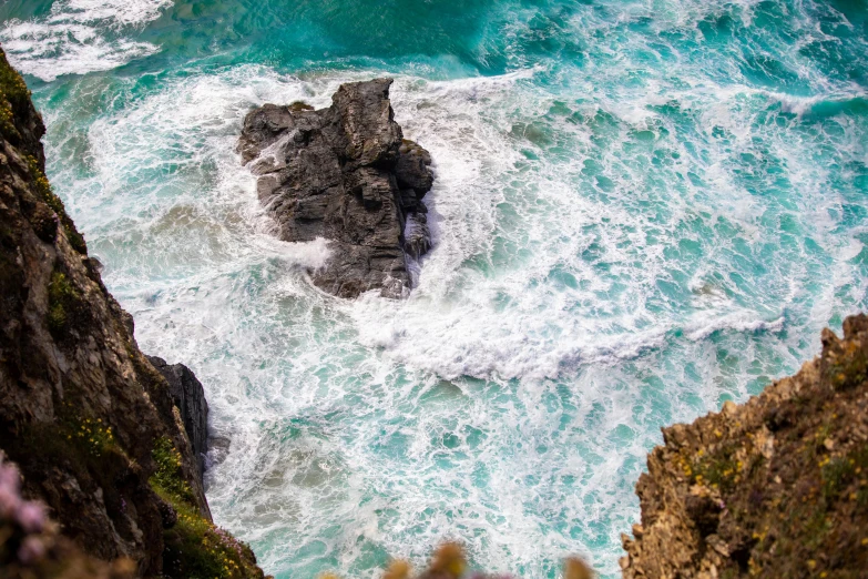 a rocky shore next to the ocean and mountains