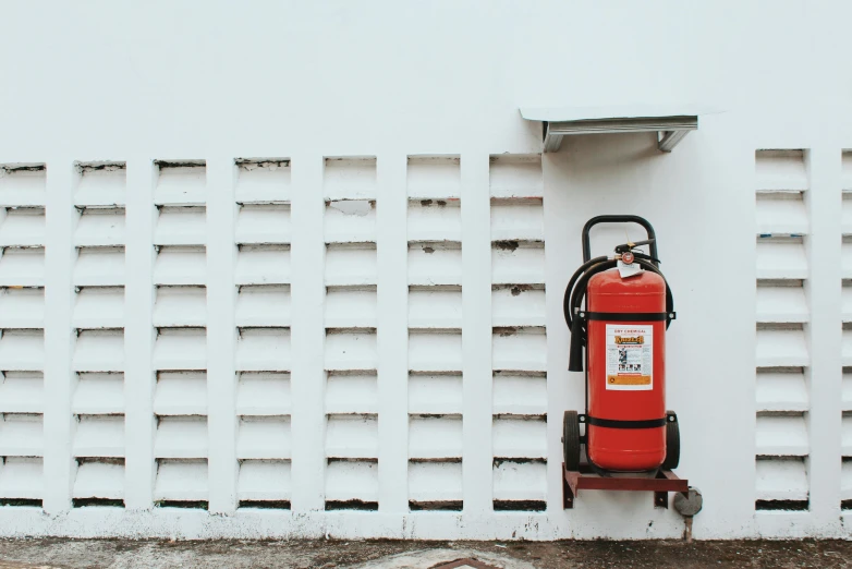 there is a fire extinguisher against a white wall