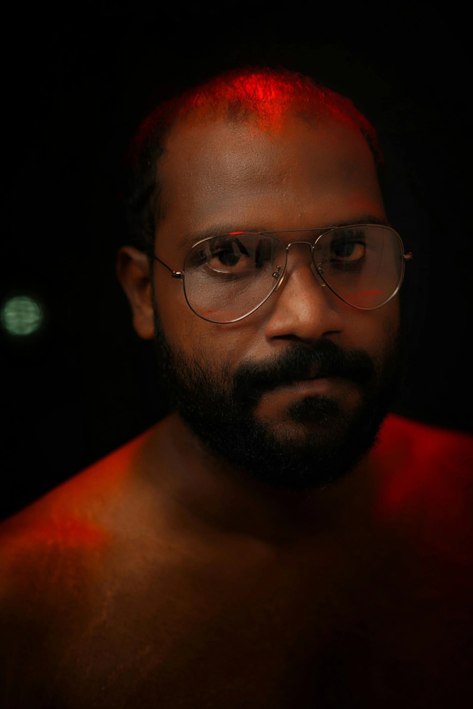 man with glasses and a beard and  in the dark