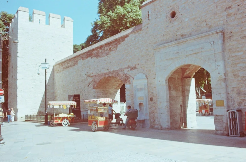 there are two carts driving near a stone wall