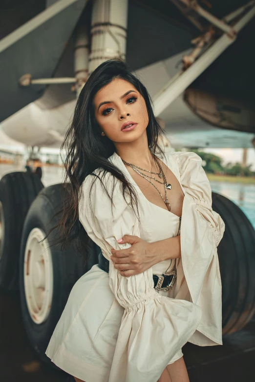 a woman poses next to an airplane with her arms on the hips