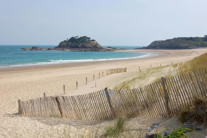 a sandy beach near the ocean with several fences