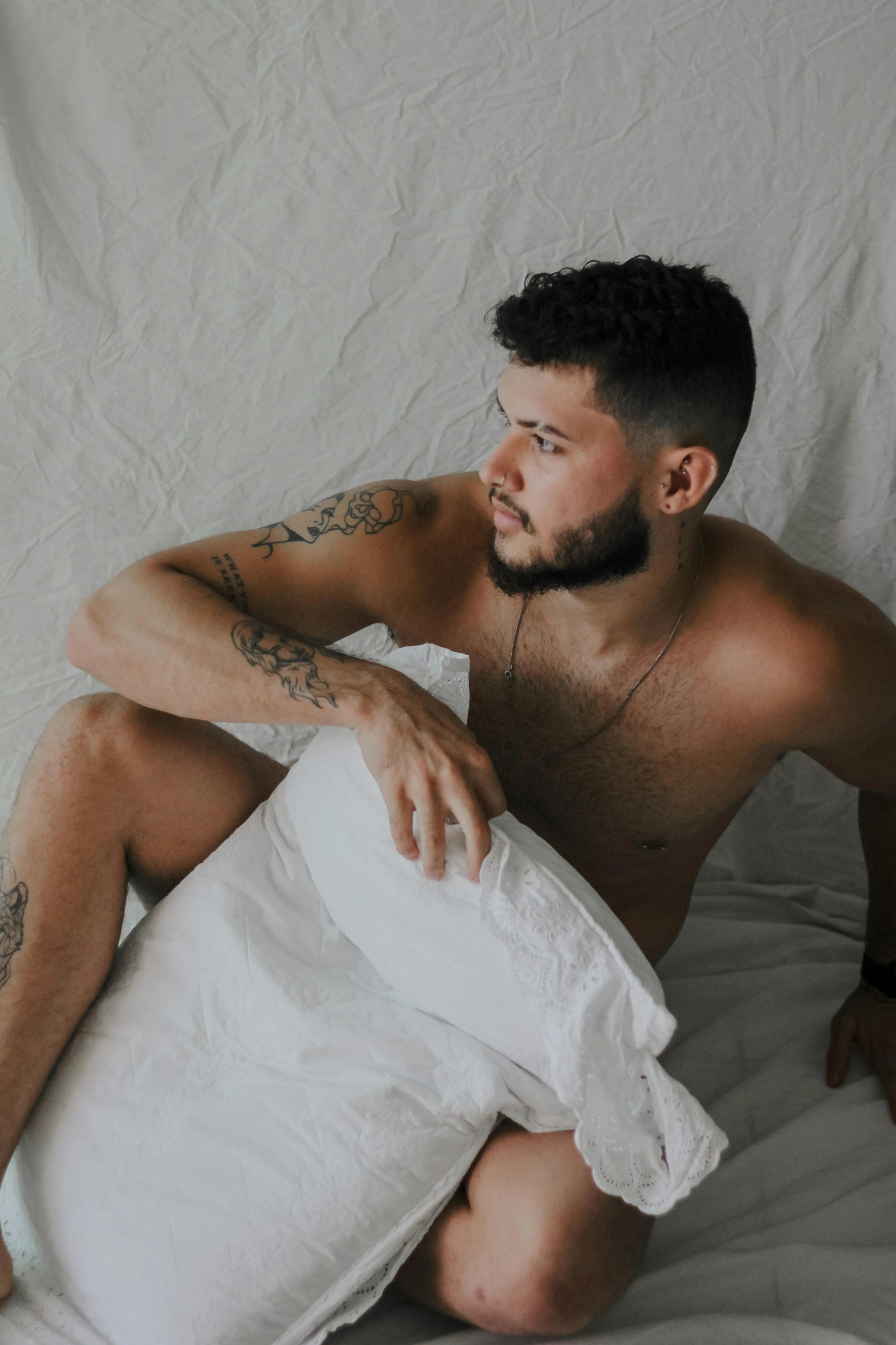 man in white sheet with beard sitting on a bed