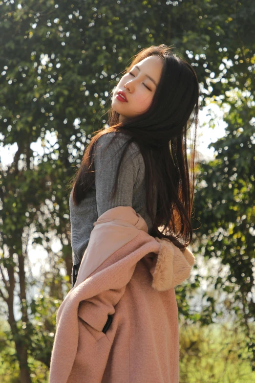 young asian woman looking up while wearing coat outdoors