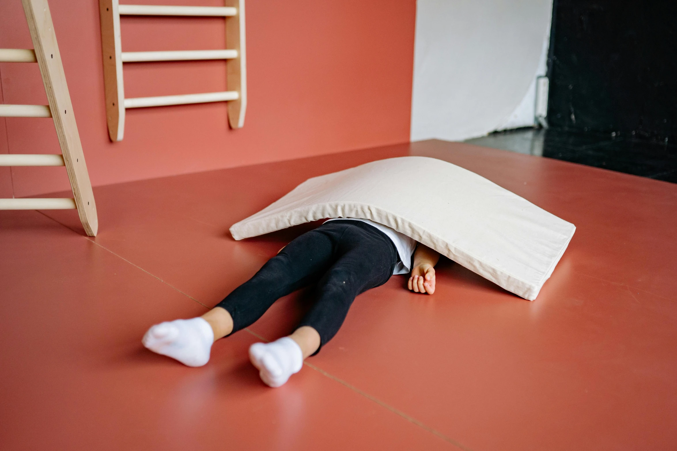 a small doll laying on the floor with a pillow on her back